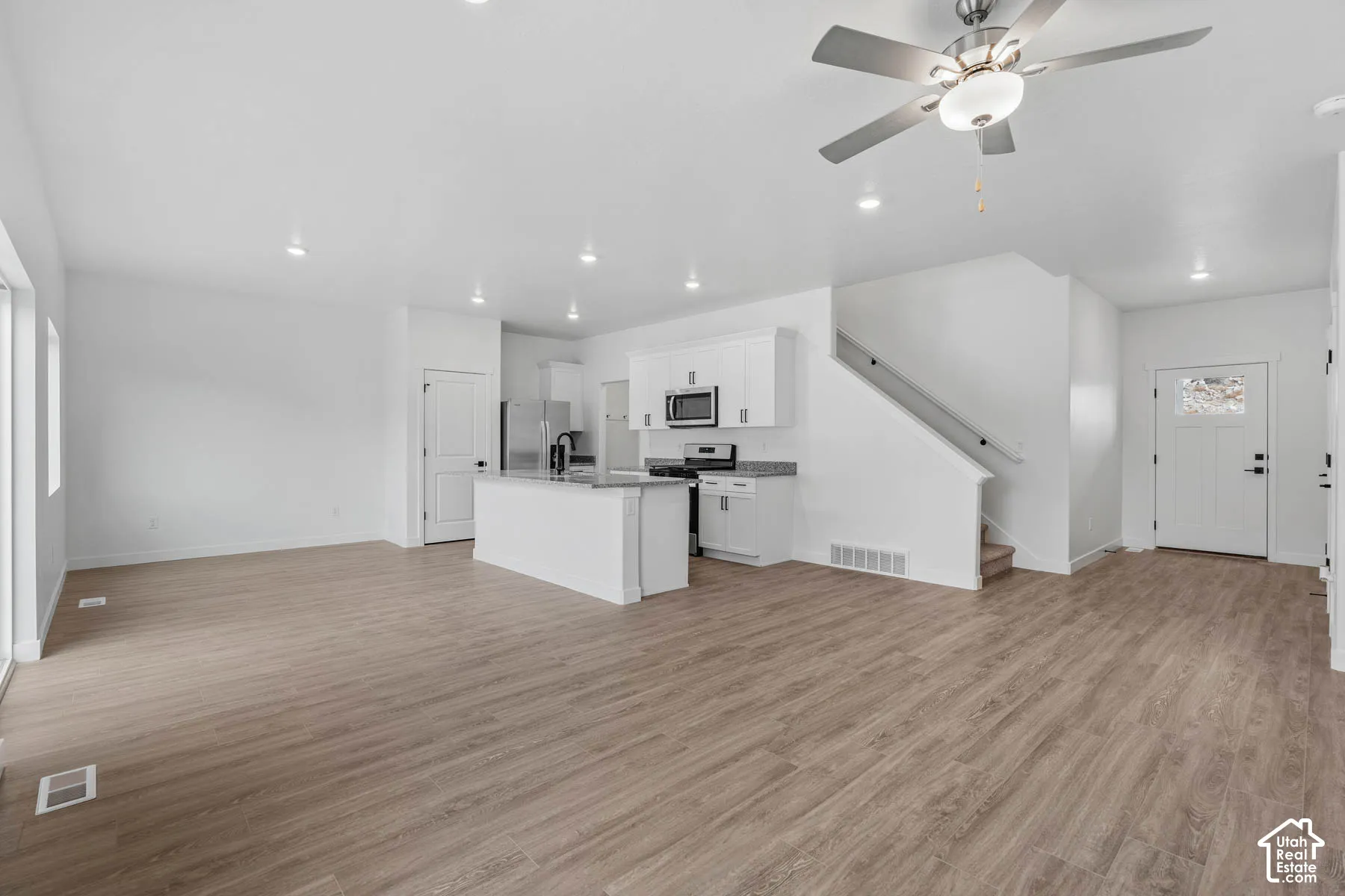 Open-concept living area with wood-finish flooring, recessed lighting, and a contemporary ceiling fan
