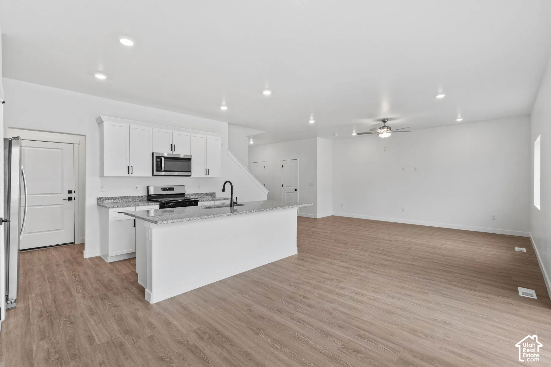 Open-concept living space with wood-finish flooring, recessed lighting, and a ceiling fan