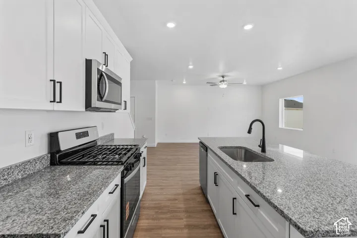 Kitchen featuring white cabinetry with matte black hardware, stainless steel appliances, and granite countertops