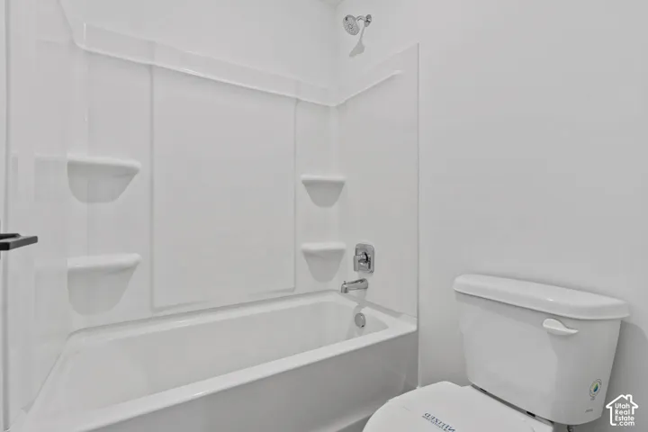 White bathtub with an integrated shower surround and chrome fixtures
