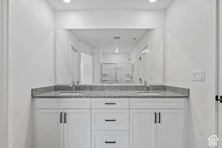 Double vanity with white cabinetry, dual undermount sinks, and a speckled countertop