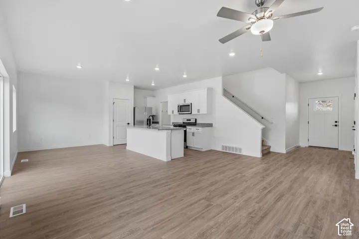 Open-concept living area with wood-finish flooring, recessed lighting, and a contemporary ceiling fan