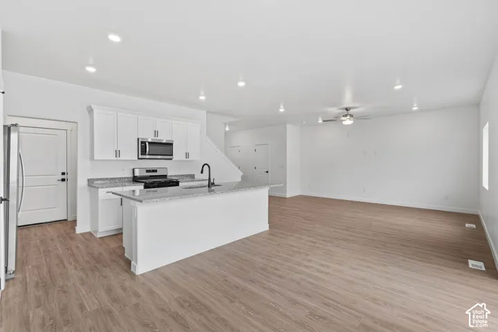 Open-concept living space with wood-finish flooring, recessed lighting, and a ceiling fan