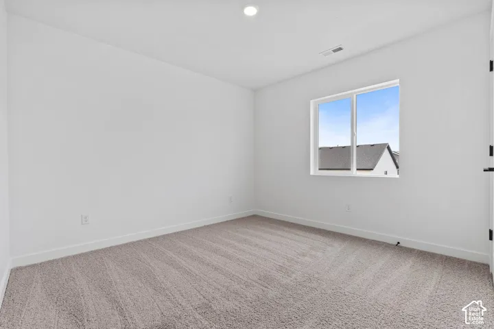 Neutral-toned carpet flooring, white walls, recessed ceiling lighting, and a double-pane window