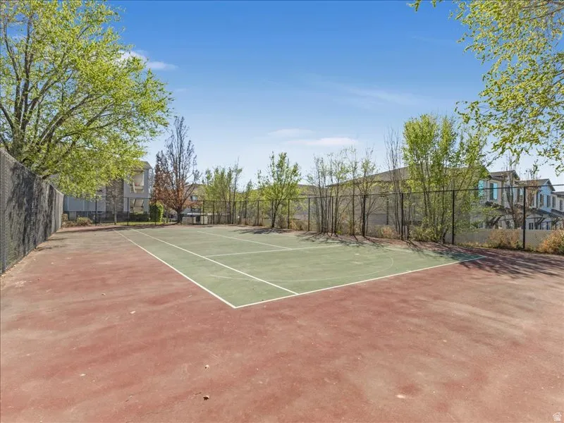 Recreational court with a hard surface, perimeter fencing, and surrounding landscaping