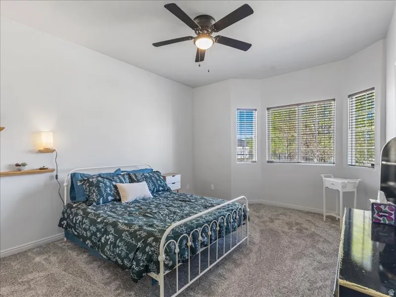 Recessed wall with multiple windows, overhead ceiling fan with lighting, wall-mounted shelving with integrated lighting, and carpeted flooring