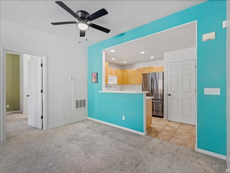 Recessed kitchen with wood-finish cabinetry, stainless steel appliances, and a white countertop