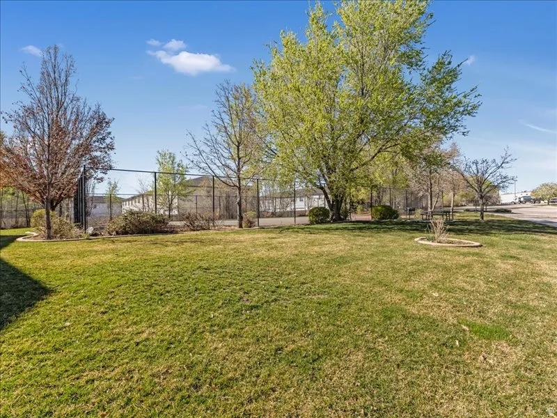 Expansive lawn area, mature trees, and a black chain-link fence