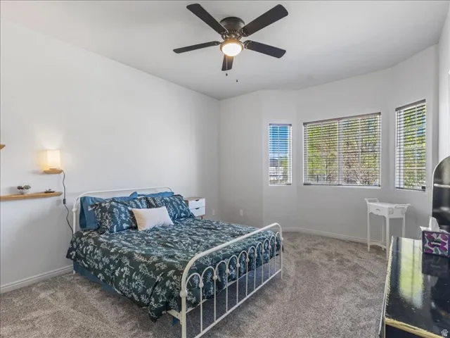 Recessed wall with multiple windows, overhead ceiling fan with lighting, wall-mounted shelving with integrated lighting, and carpeted flooring