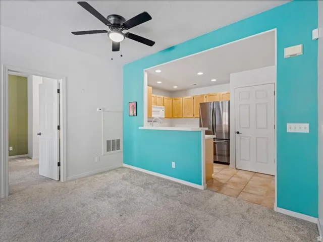 Recessed kitchen with wood-finish cabinetry, stainless steel appliances, and a white countertop