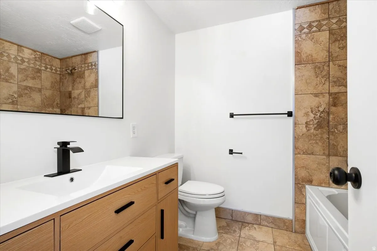 Wood-finish vanity with an integrated white sink, black modern faucet, and black hardware