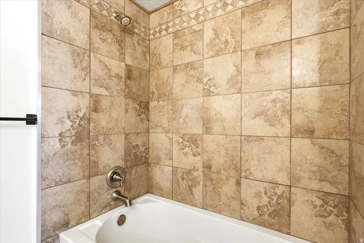 Bathtub with tiled surround, decorative accent tile border, and brushed nickel fixtures