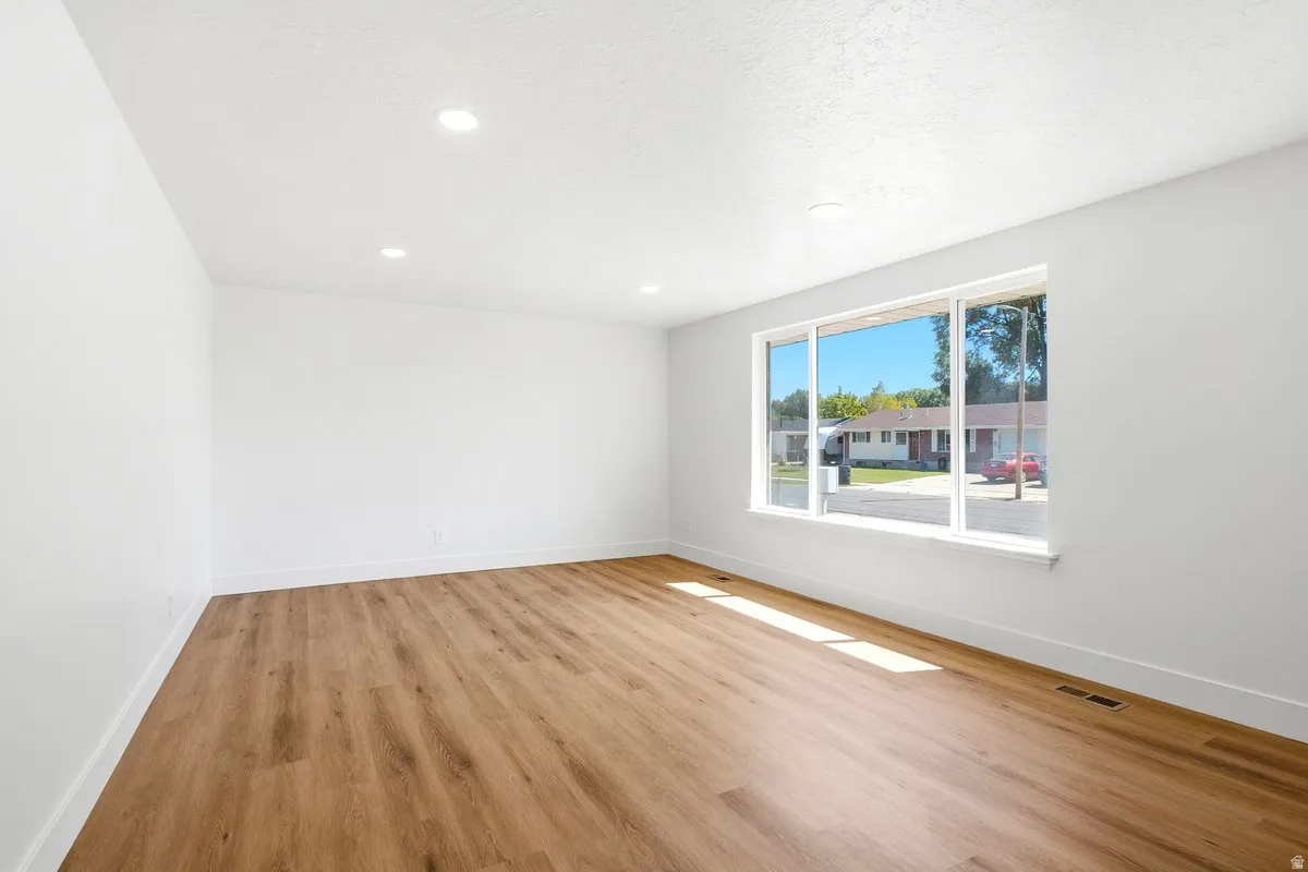 Recessed ceiling lighting, wood-finish flooring, white wall finishes, and a large window with white trim