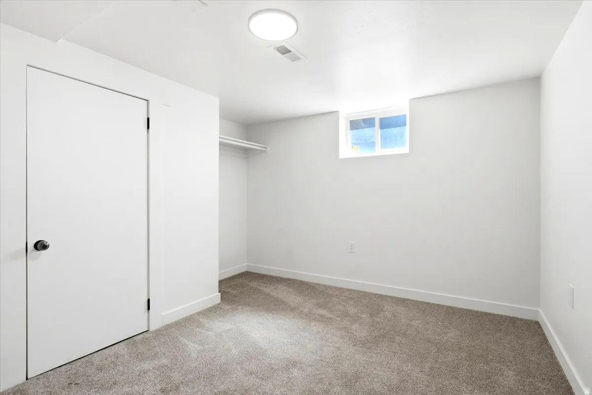 Carpeted room featuring a single window, white walls, and a closet with a built-in hanging rod