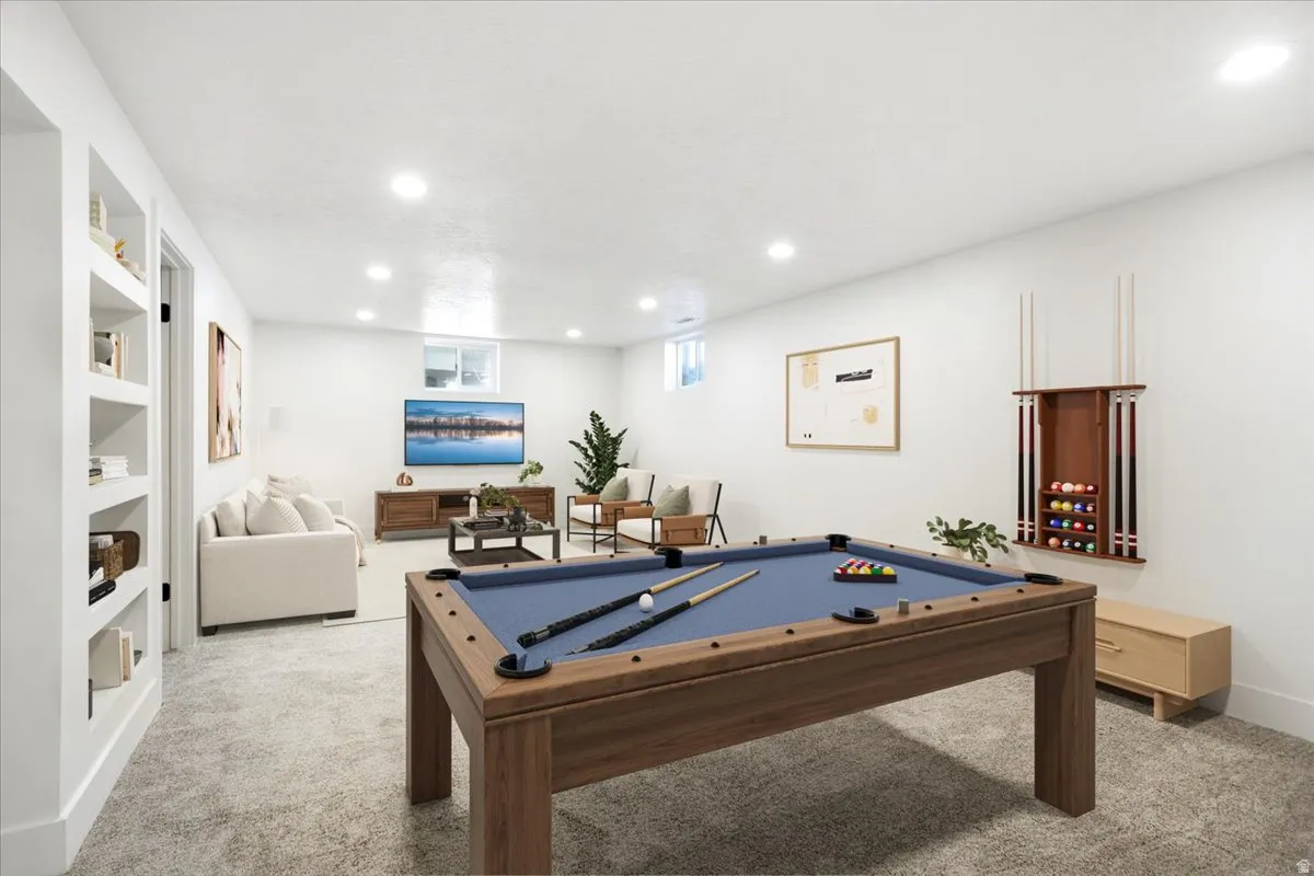 Recessed lighting illuminates this expansive room, featuring built-in shelving, a wood-finish pool table, and a dedicated pool cue rack