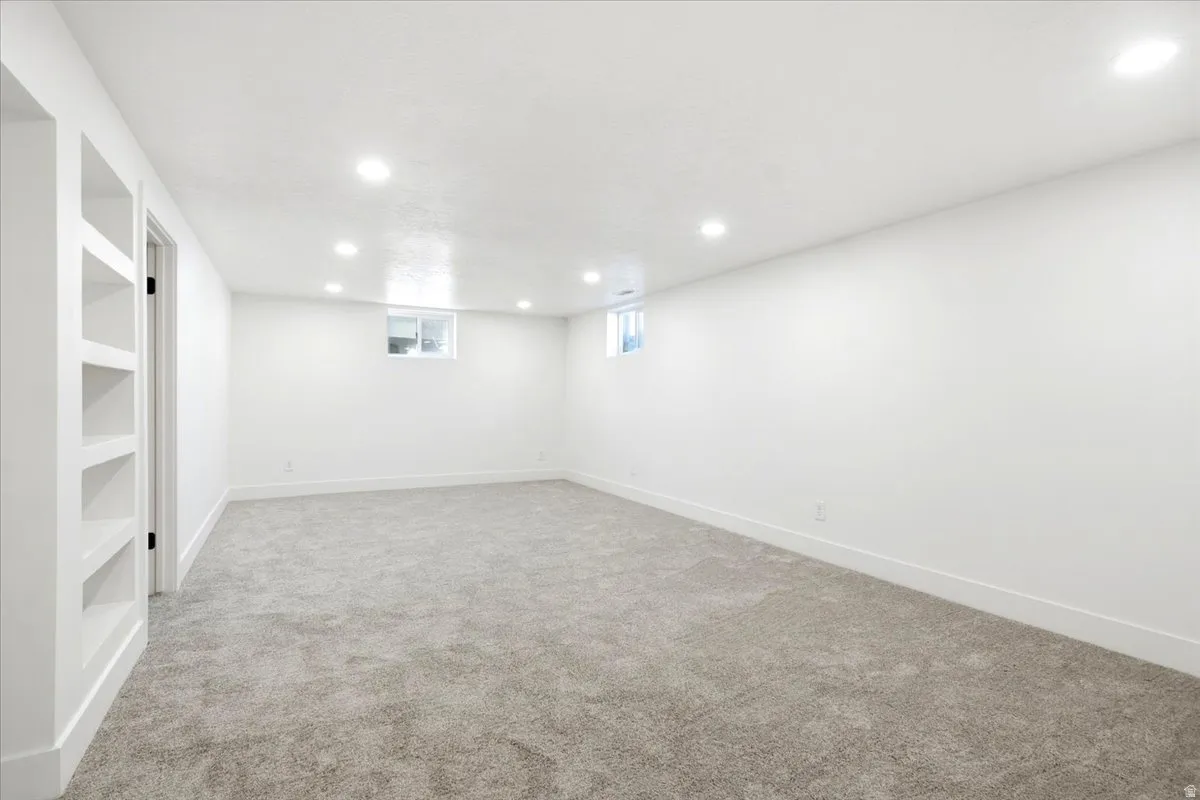 Spacious room with recessed lighting, built-in shelving, plush carpeting, and white trim