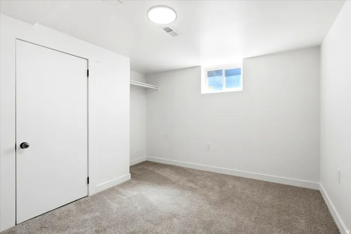 Carpeted room featuring a single window, white walls, and a closet with a built-in hanging rod