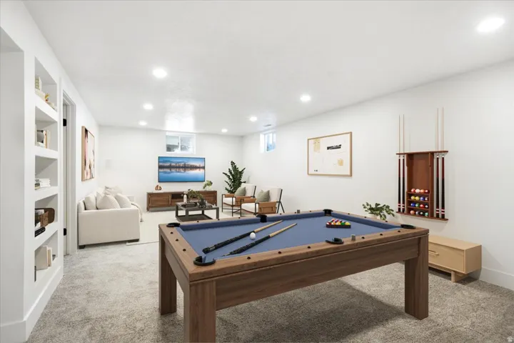 Recessed lighting illuminates this expansive room, featuring built-in shelving, a wood-finish pool table, and a dedicated pool cue rack