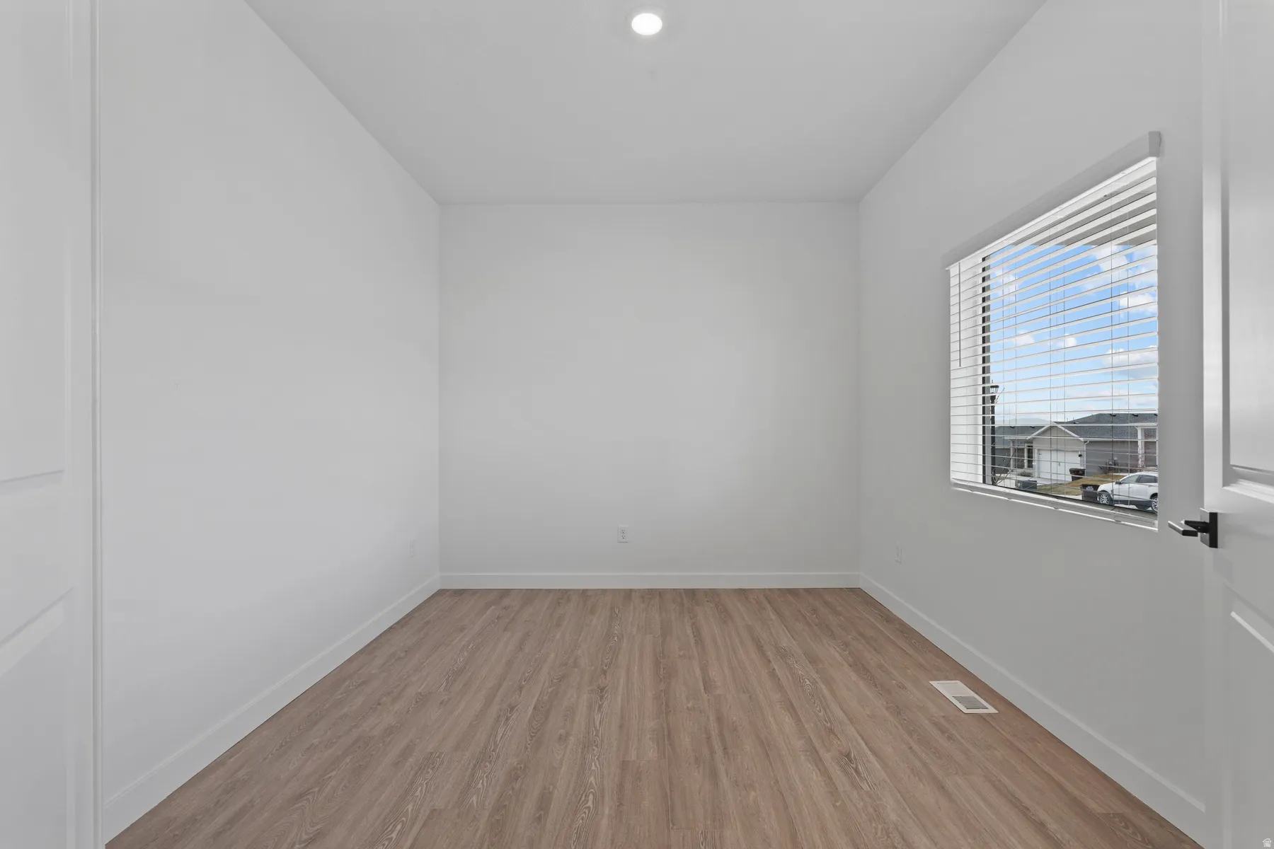 Neutral wall color, wood-finish flooring, recessed ceiling lighting, and a window with blinds