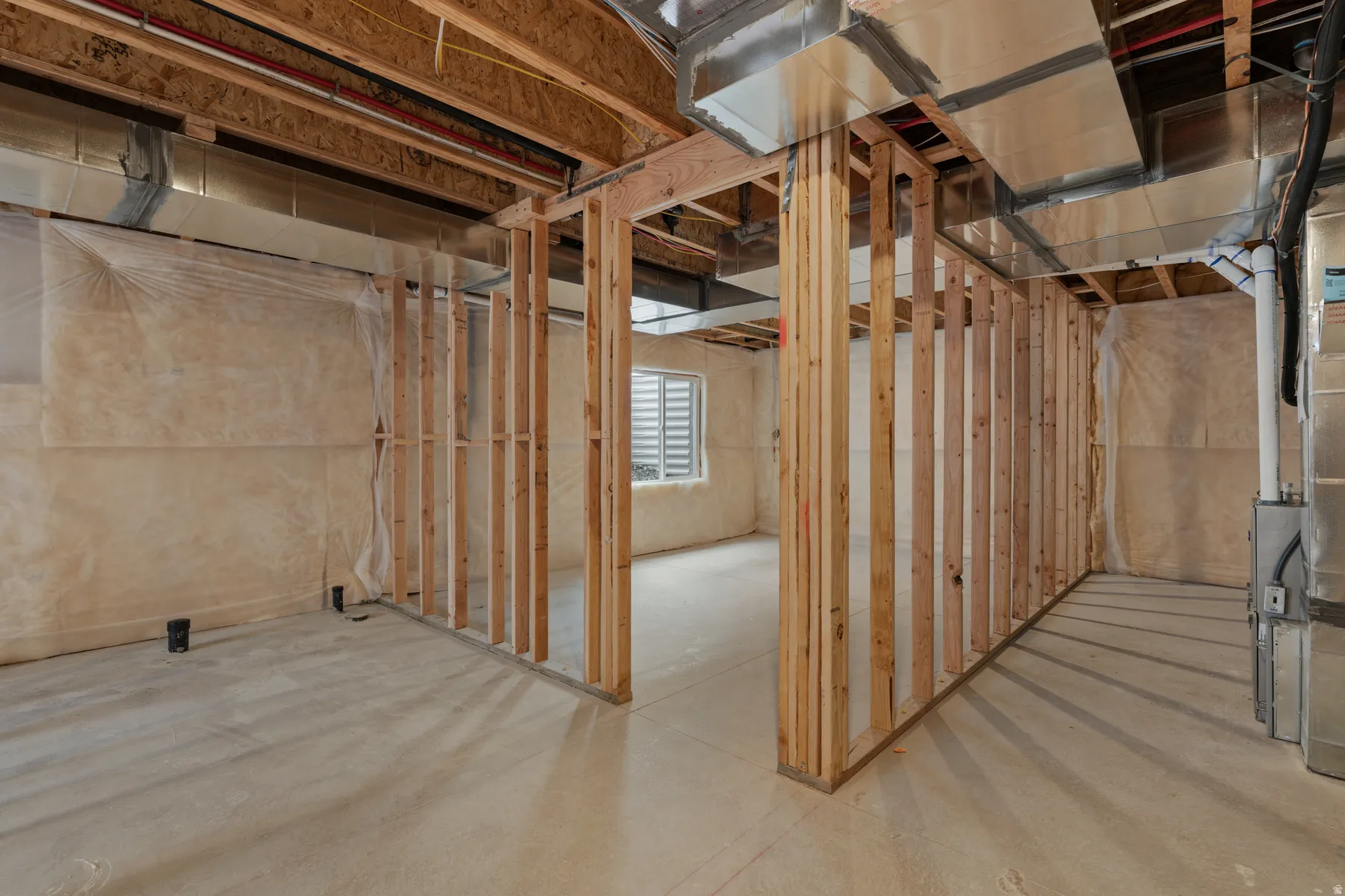 Unfinished lower level with wood framing, exposed ductwork, concrete flooring, and a single window with horizontal blinds