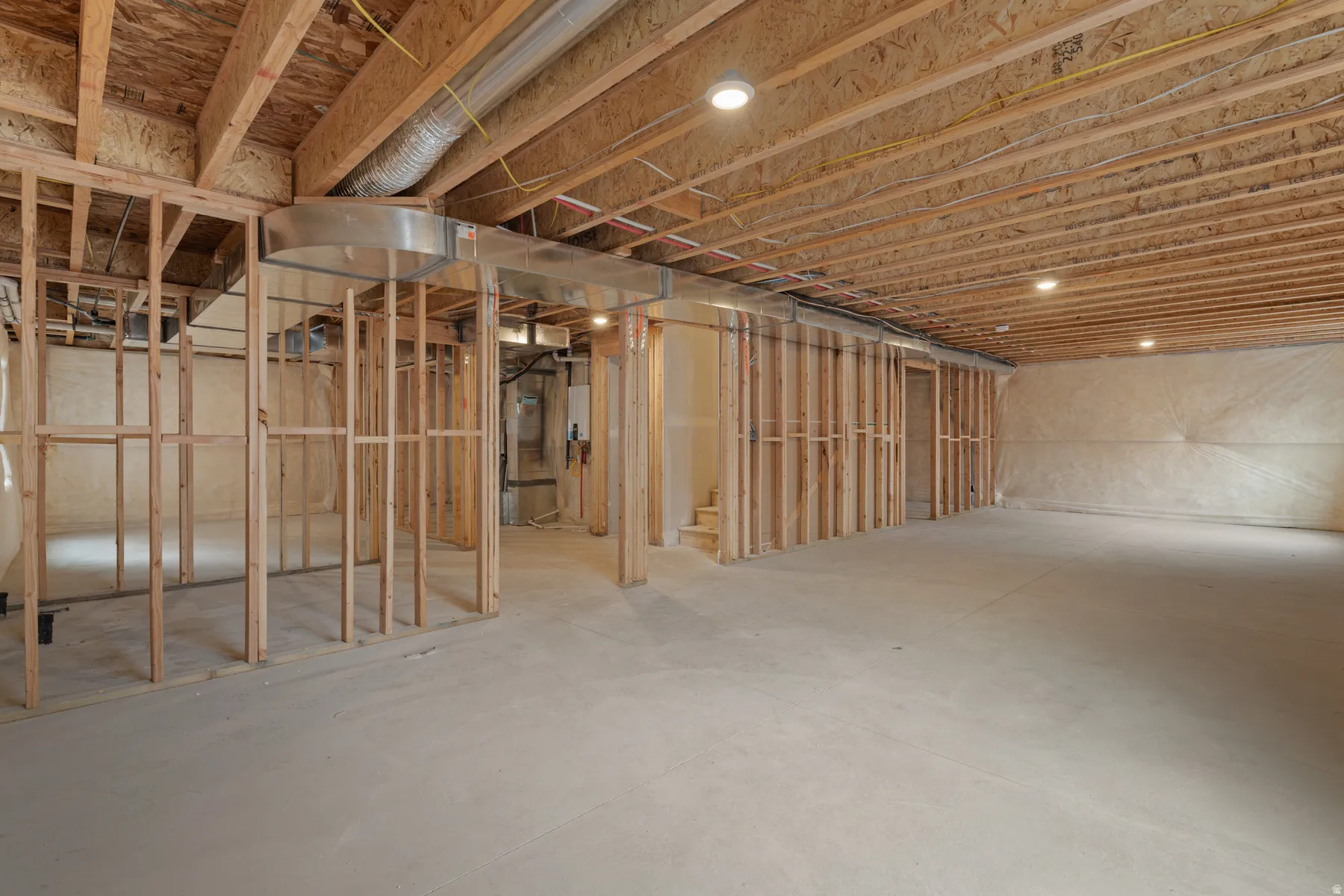 Unfinished basement with exposed ceiling joists, concrete flooring, recessed lighting, and framed interior walls