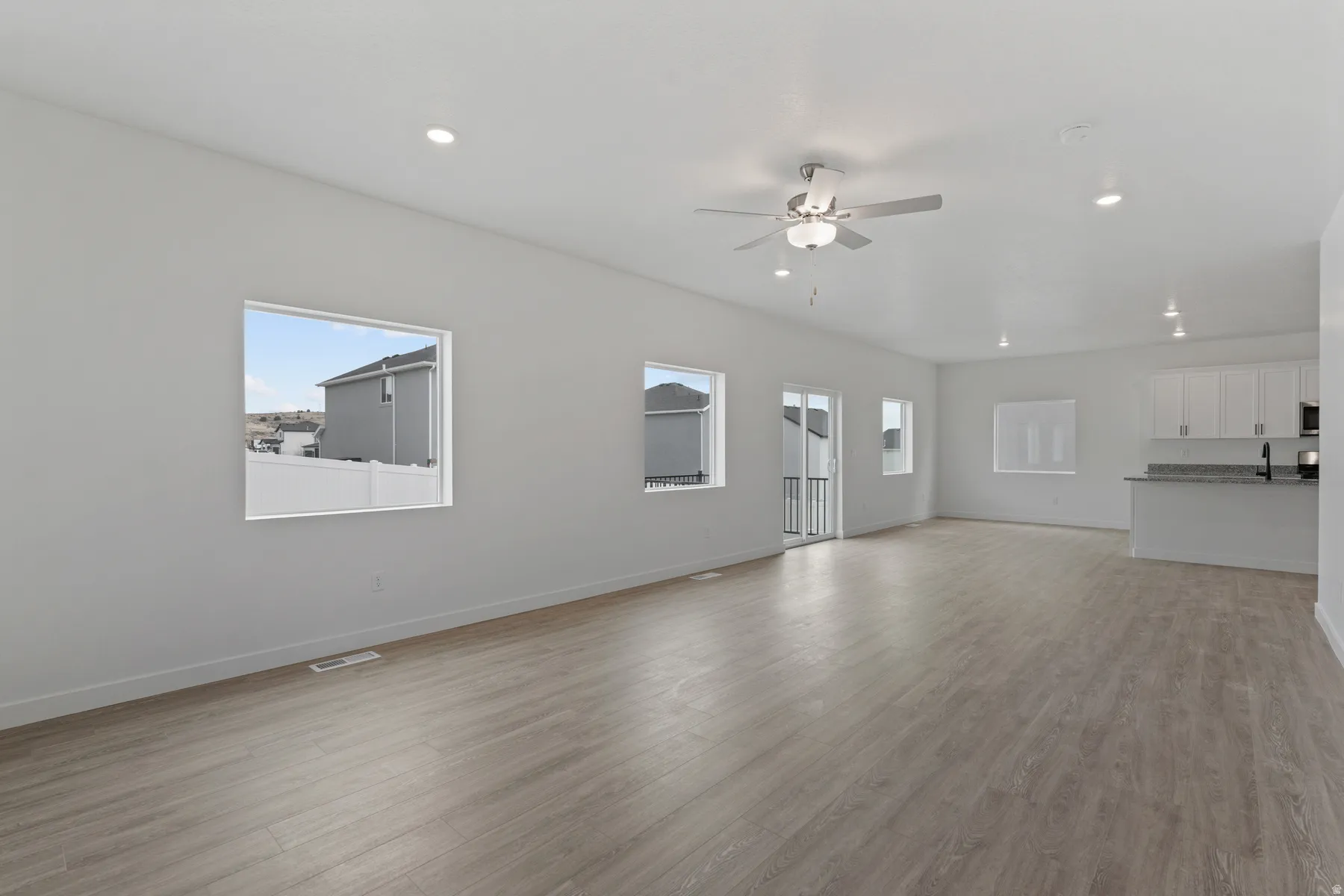 Open-concept living area with wood-finish flooring, recessed lighting, and a ceiling fan