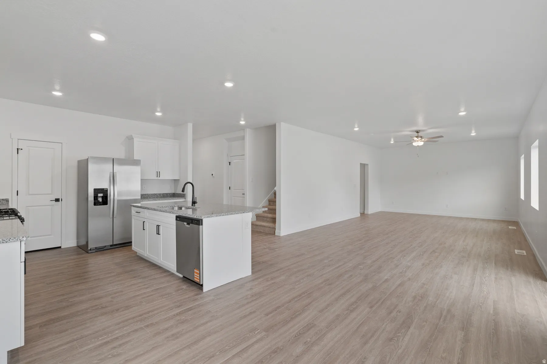 Open-concept main level featuring wood-finish flooring, recessed lighting, and a kitchen island with sink