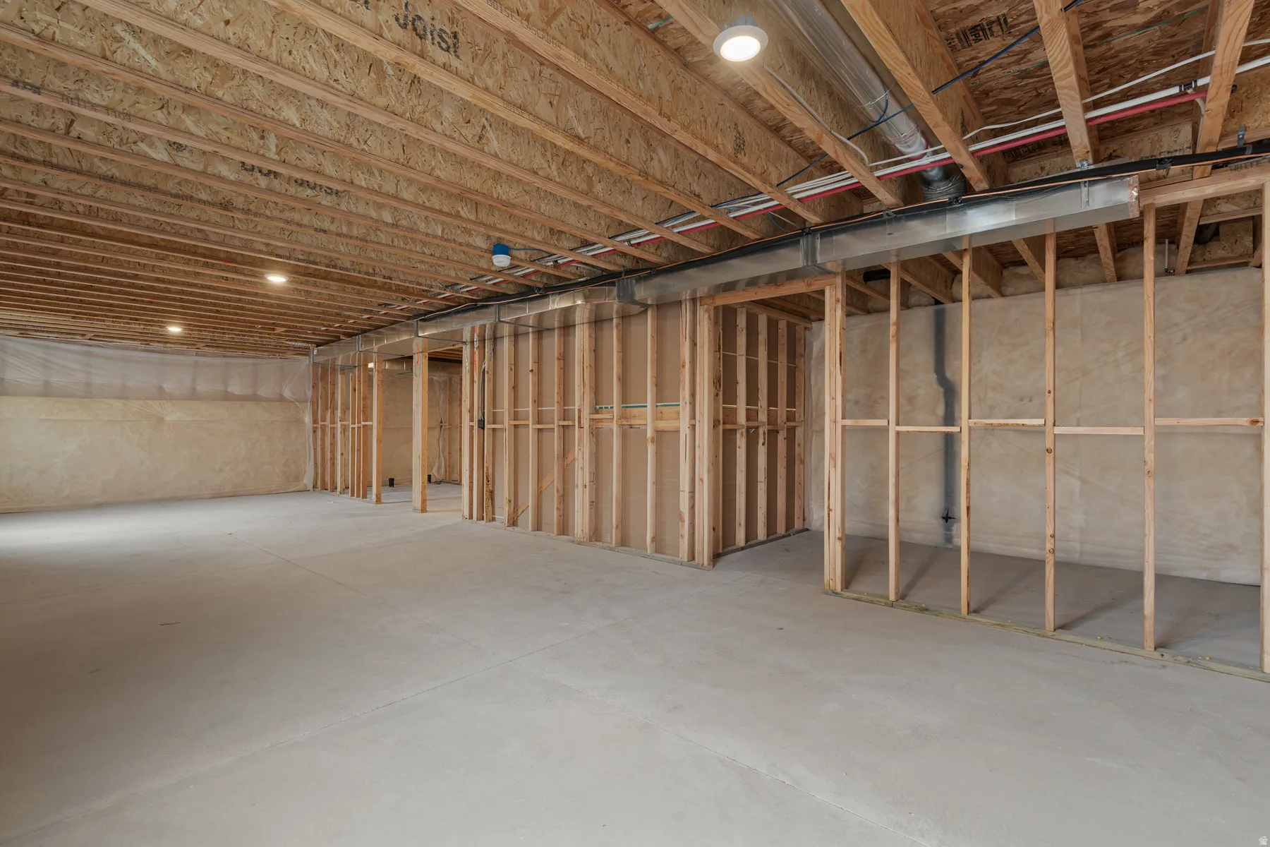 Unfinished basement with concrete flooring, exposed wood framing, and recessed ceiling lighting