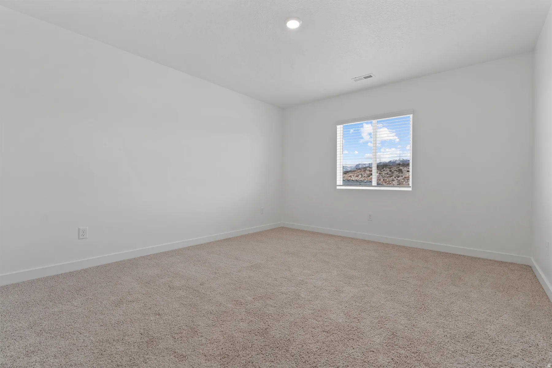 Neutral color palette, recessed lighting, expansive carpeting, window with blinds