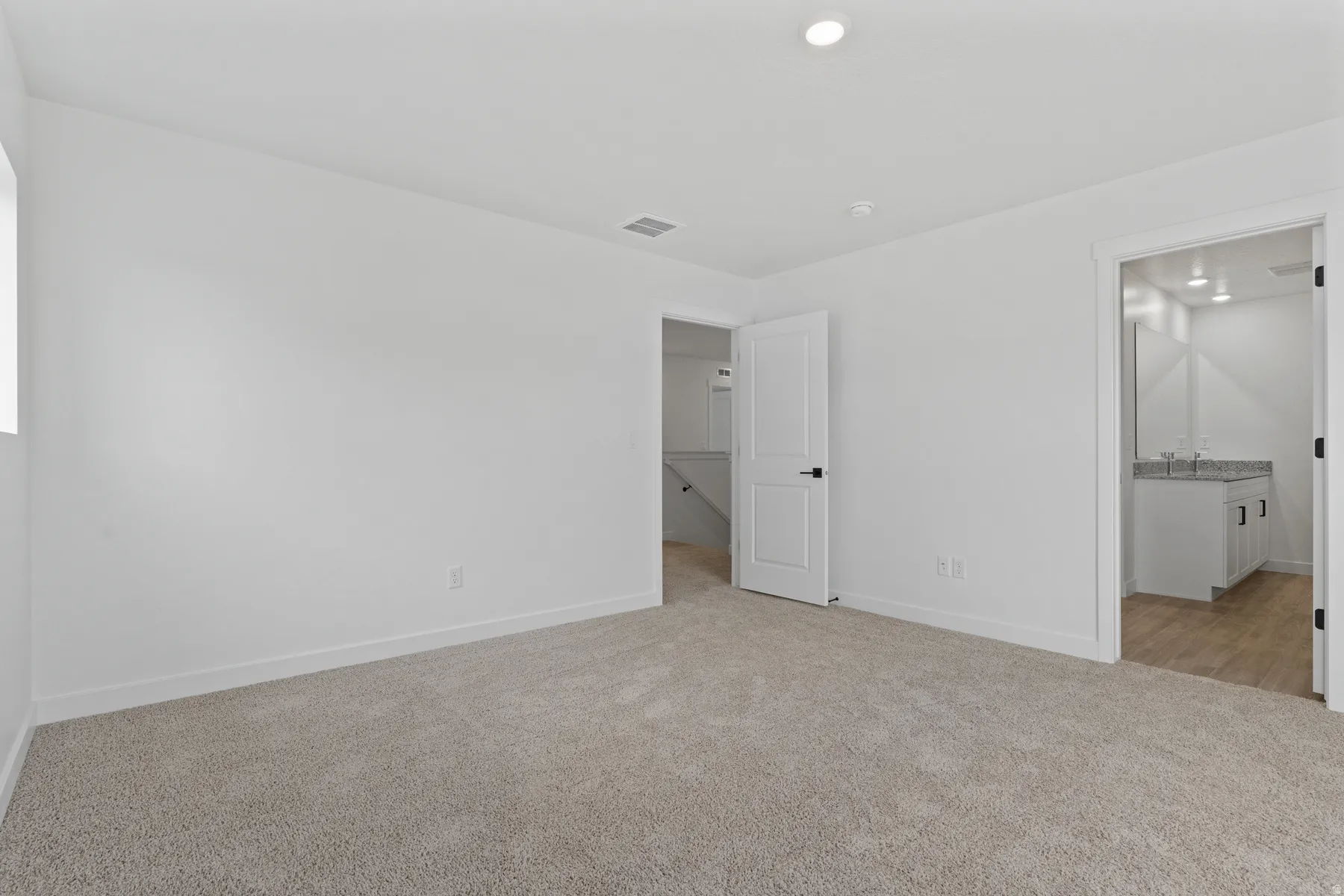 Neutral-toned carpeting and white walls with recessed lighting