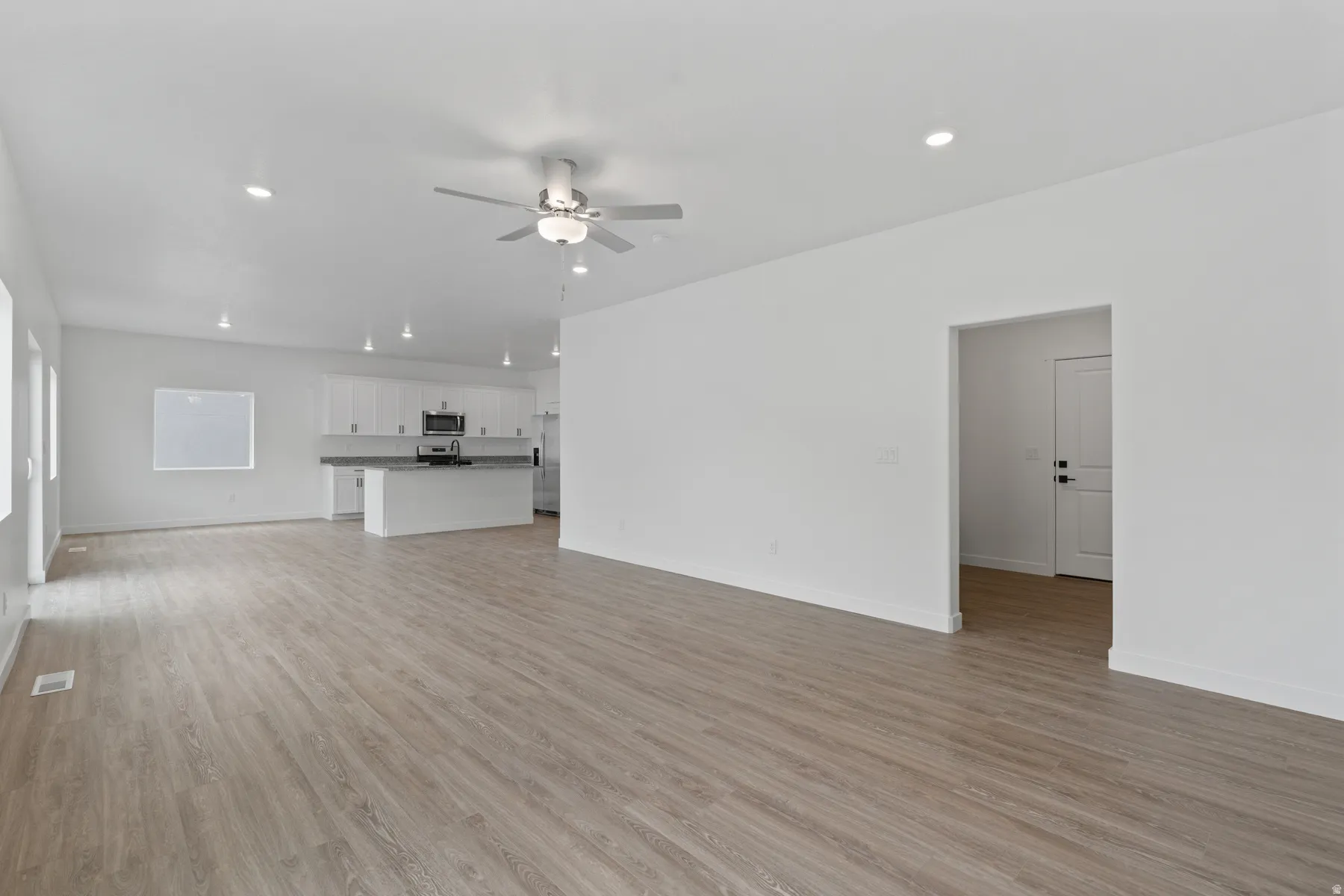 Expansive open-concept living area featuring wood-finish flooring, recessed lighting, and a ceiling fan