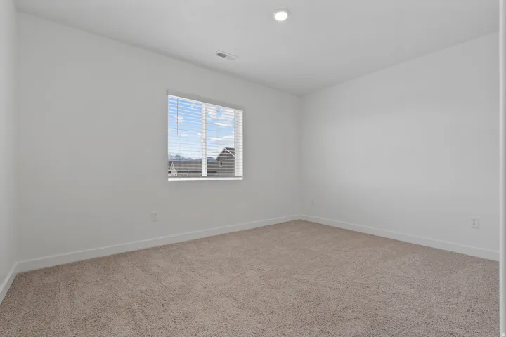 Neutral-toned carpeting, white walls, and a single window with horizontal blinds