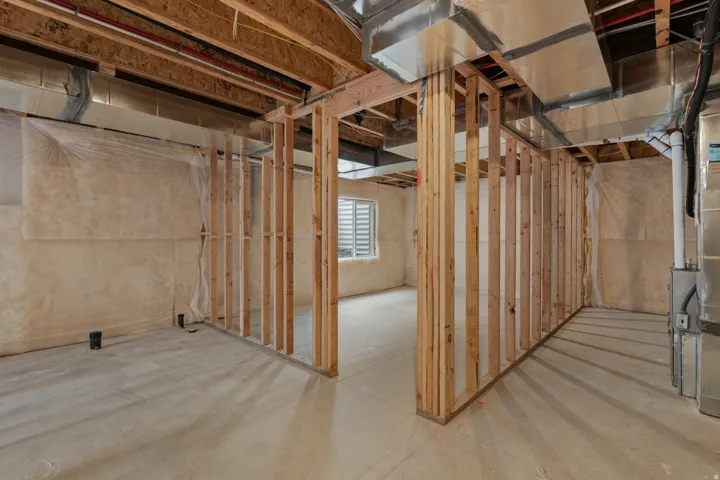 Unfinished lower level with wood framing, exposed ductwork, concrete flooring, and a single window with horizontal blinds