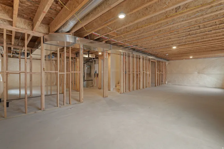 Unfinished basement with exposed ceiling joists, concrete flooring, recessed lighting, and framed interior walls