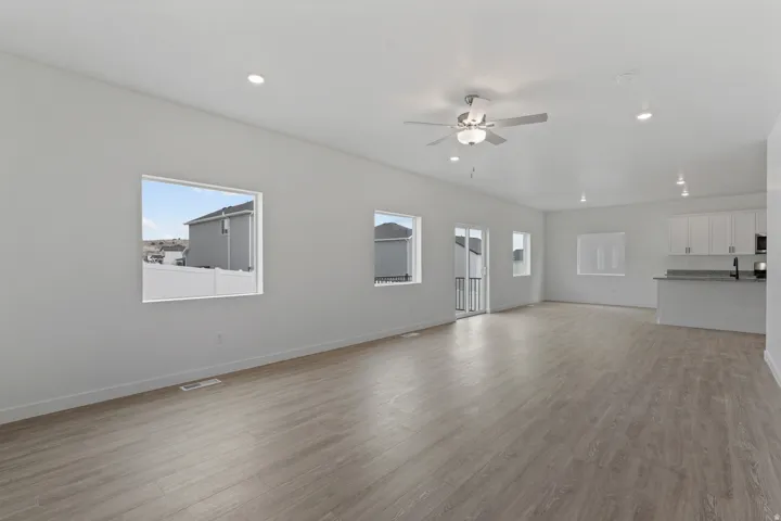 Open-concept living area with wood-finish flooring, recessed lighting, and a ceiling fan
