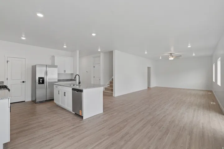 Open-concept main level featuring wood-finish flooring, recessed lighting, and a kitchen island with sink