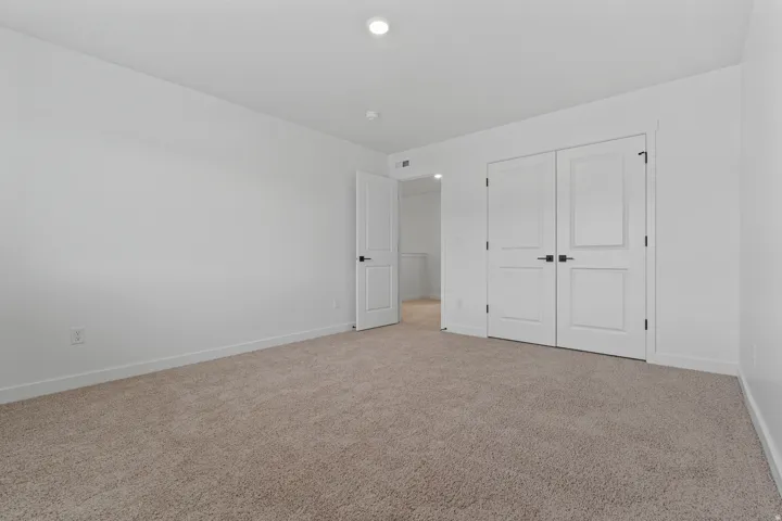 Recessed lighting illuminates the room, featuring plush carpeting and white walls