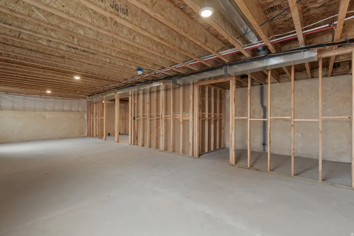 Unfinished basement with concrete flooring, exposed wood framing, and recessed ceiling lighting