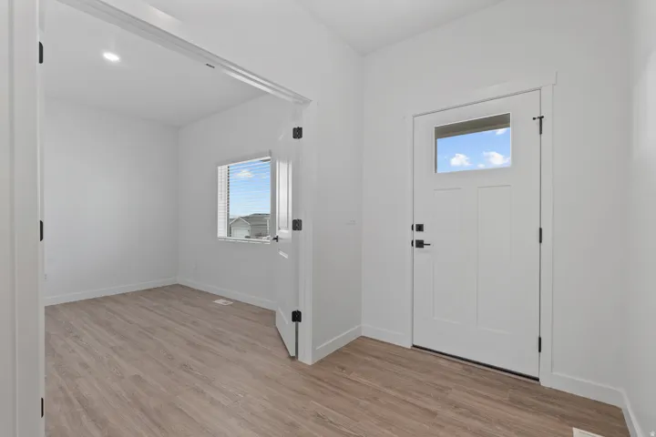 Entryway featuring wood-finish flooring, a white front door with a transom window, and modern black hardware