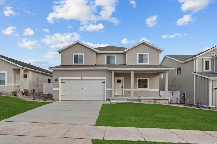 Two-story residence featuring a gray exterior, covered front porch, attached garage, and a concrete driveway