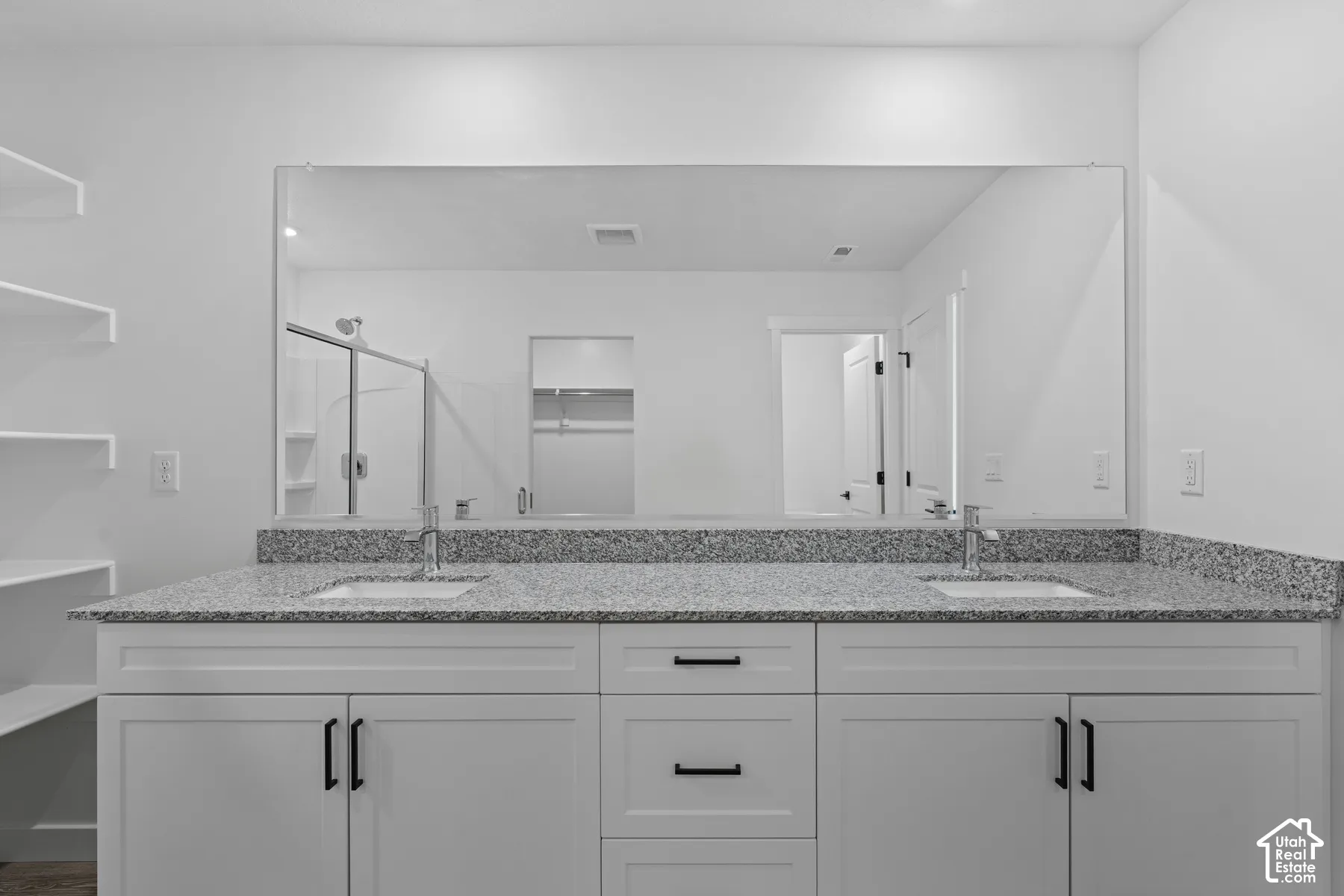 Double vanity with granite countertop, undermount sinks, and white shaker-style cabinetry