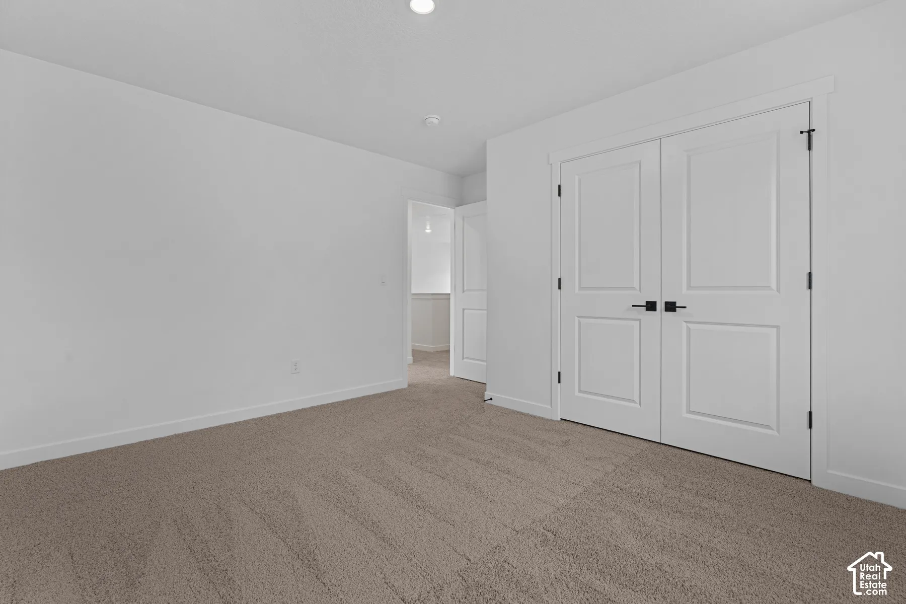 Neutral tone carpeting and white walls with recessed ceiling lighting