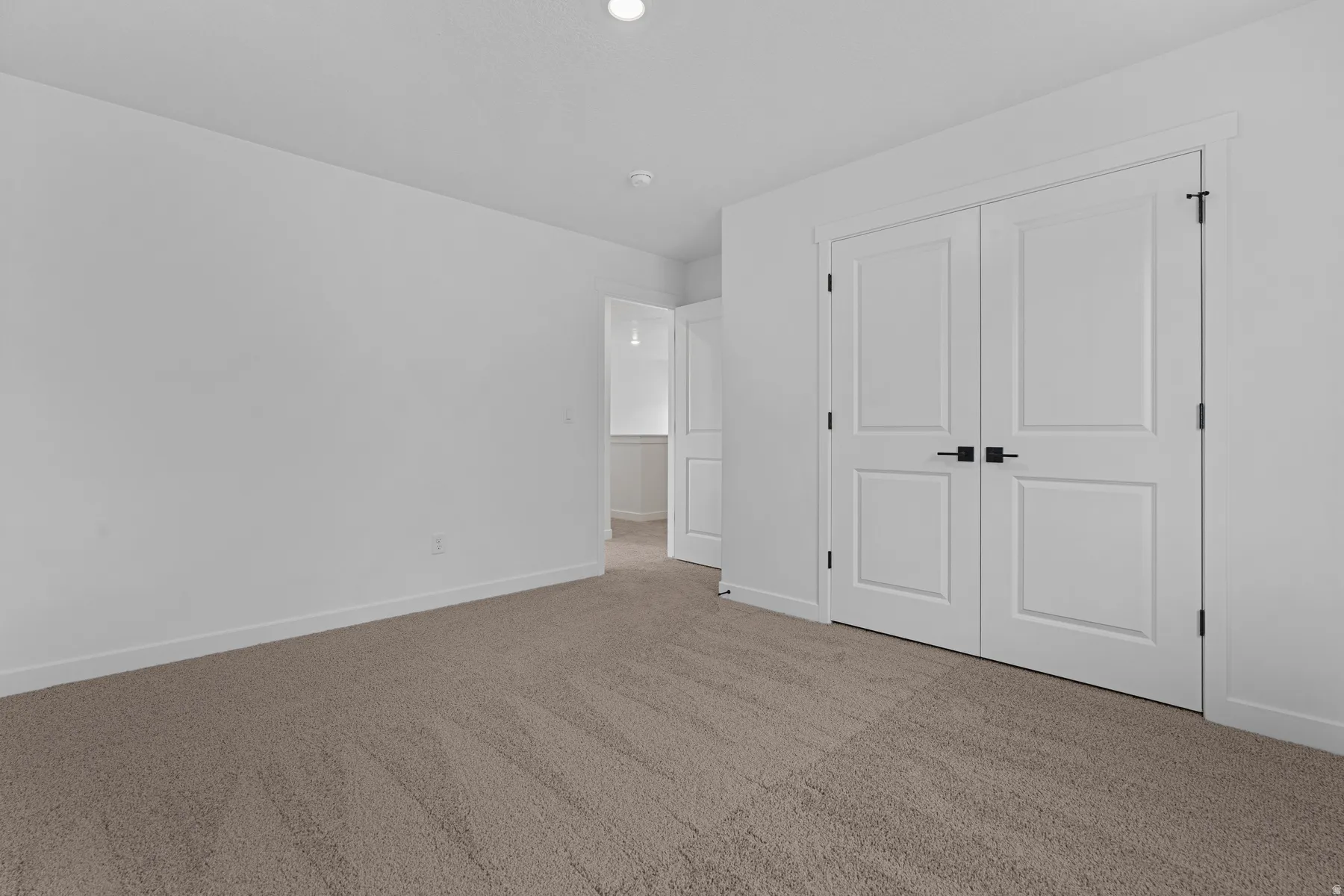 Neutral tone carpeting and white walls with recessed ceiling lighting