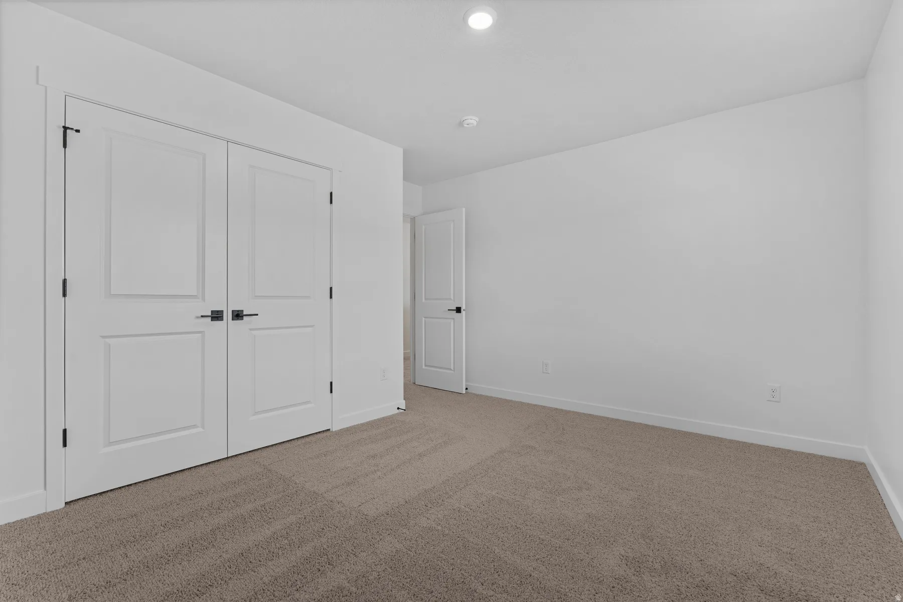 Neutral-toned carpeting, white walls, and a white ceiling with recessed lighting