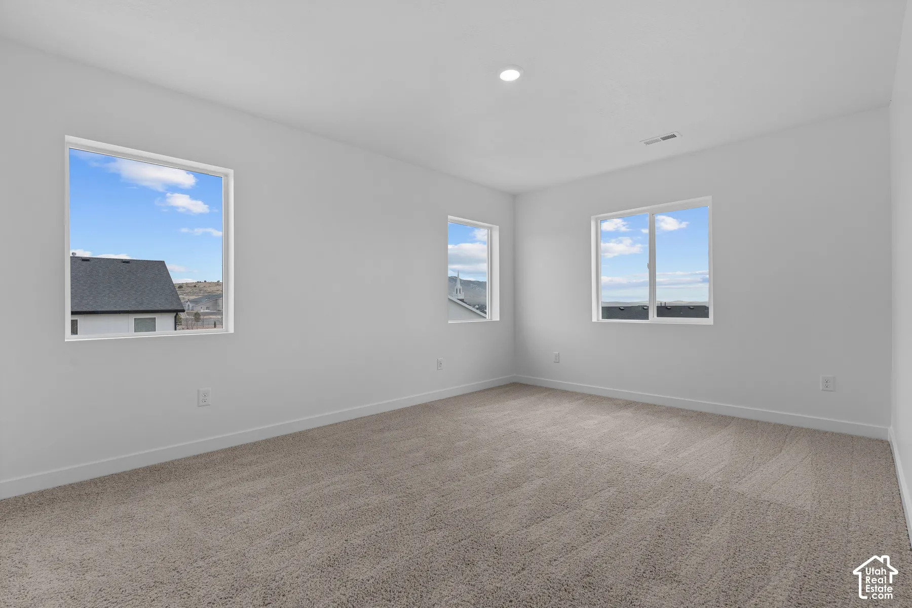Neutral-toned carpeting, white walls, and multiple windows providing ambient light