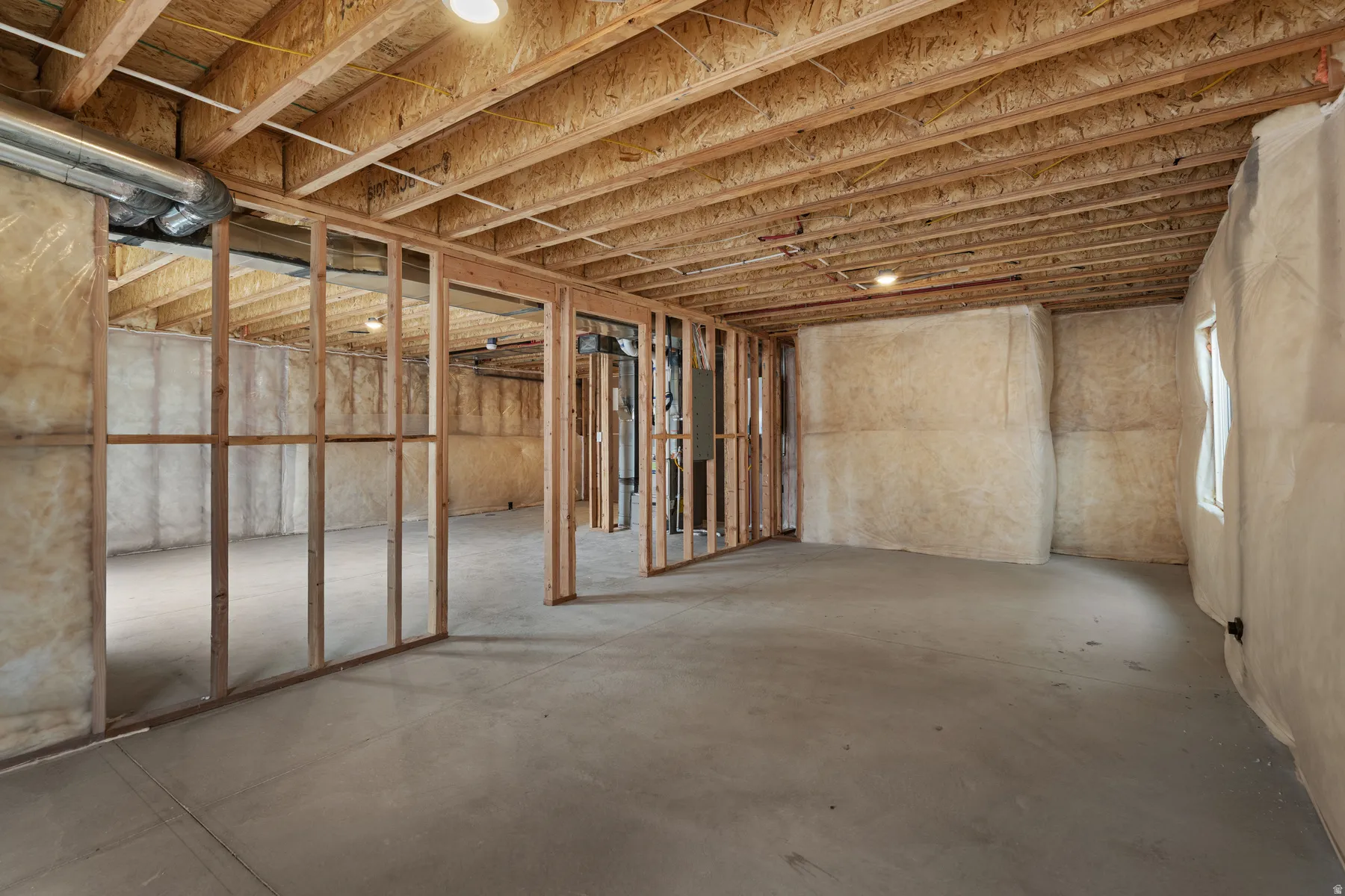 Unfinished basement featuring wood framing, concrete flooring, exposed ceiling joists, recessed lighting, and insulated walls