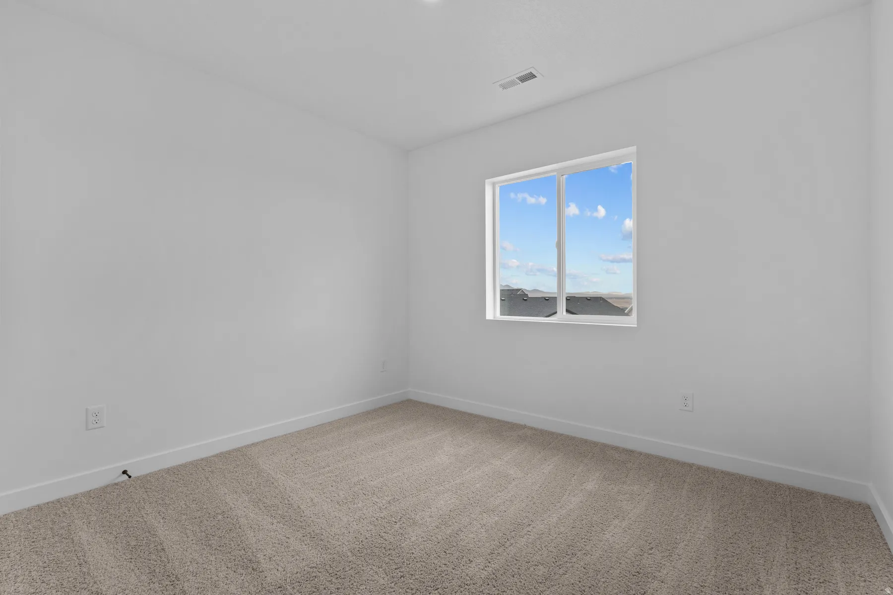 Neutral-toned carpeted flooring with a white trim, large window with white framing, and white painted walls