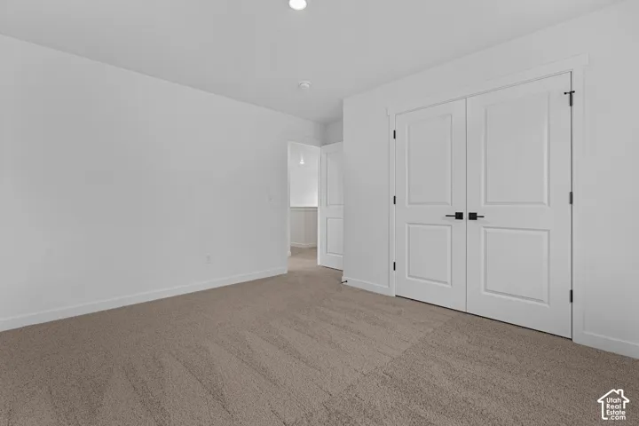 Neutral tone carpeting and white walls with recessed ceiling lighting