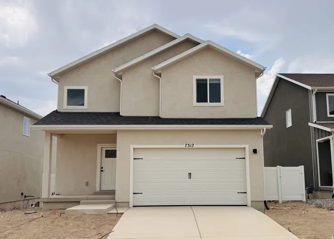 Two-story stucco exterior with a two-car garage, covered porch, and concrete driveway