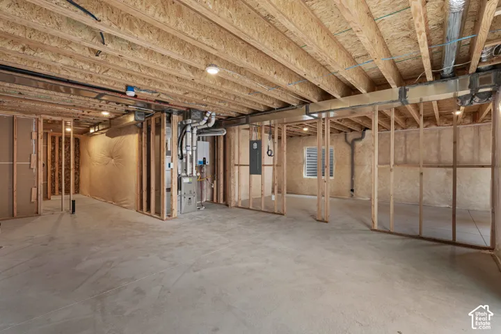 Unfinished basement with concrete flooring, exposed wood framing, and visible utility systems